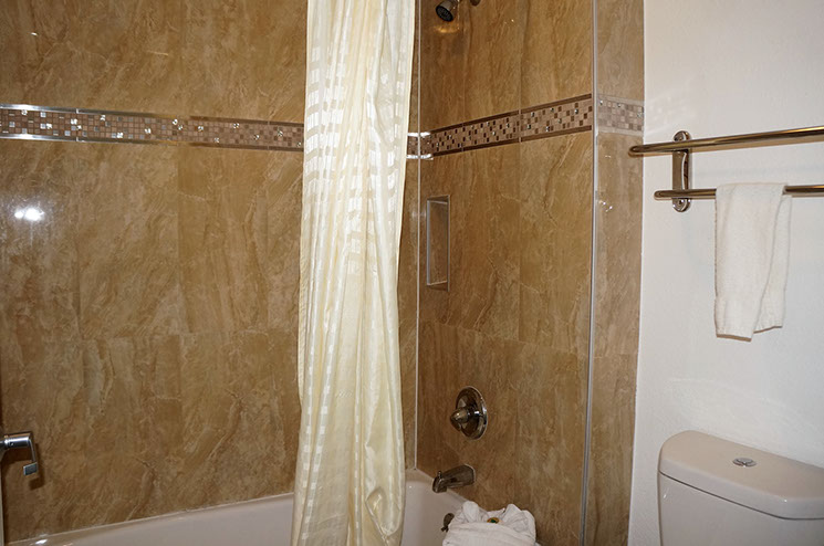 Photo showing guest bathroom with tub and shower combination. Towel rack on wall above commode.